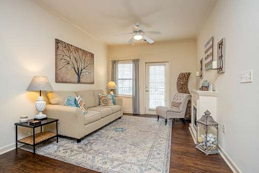 A living room with a beige couch, a chair, and a rug.