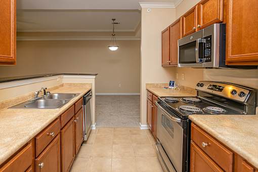 A kitchen with a stove, sink, and cabinets.