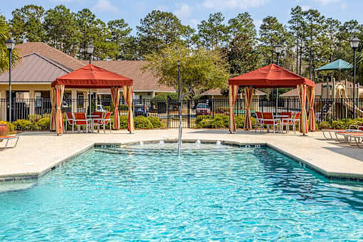 A pool with a red canopy and a slide in the background.