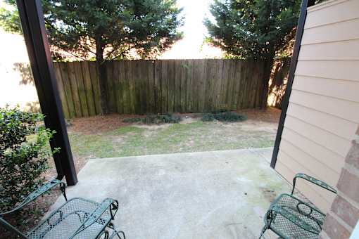a backyard patio with two chairs and a fence