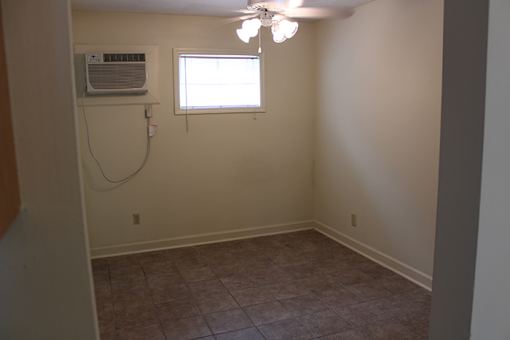 an empty room with a ceiling fan and a window