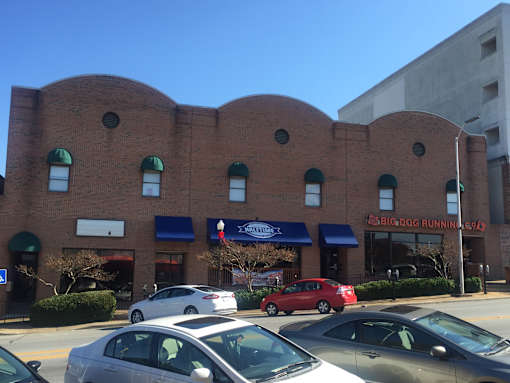 a view of the front of a brick building with cars parked in front