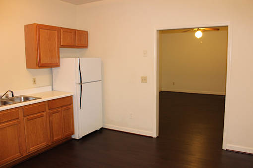 an empty kitchen with a white refrigerator and wooden cabinets