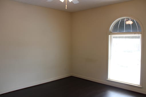 an empty living room with a large window and wooden floors