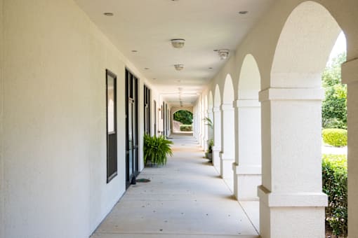 A long hallway with arches and plants on the side.