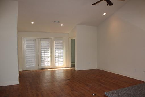 an empty living room with a wood floor and white walls
