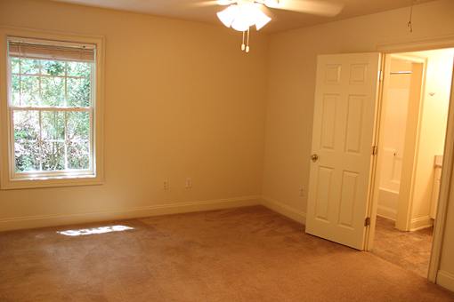 an empty living room with a white door and a window
