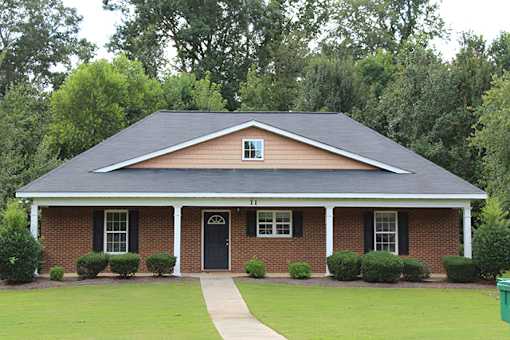 a brick house with a black roof and a sidewalk