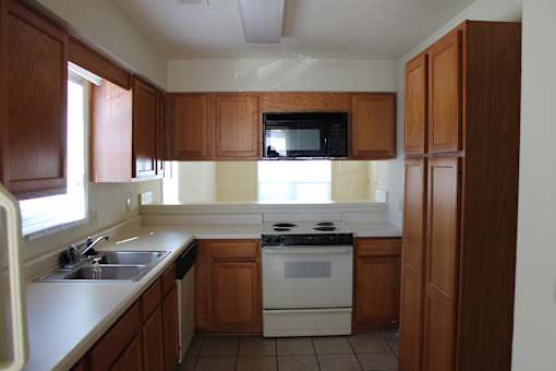 an empty kitchen with white appliances and wooden cabinets