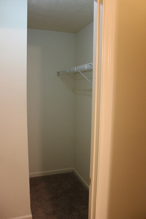 a walk in closet in a bedroom with a white closet rack