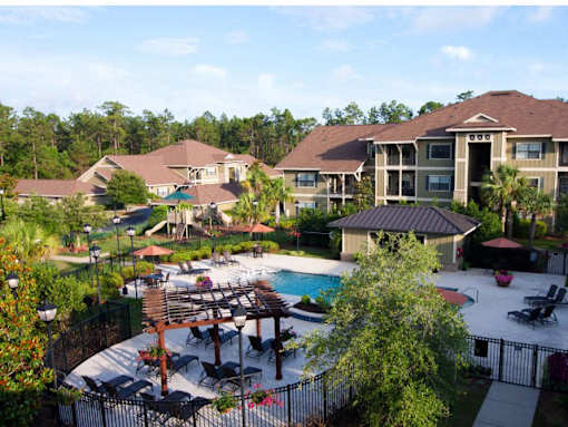 A pool area with a table and chairs and a building in the background.