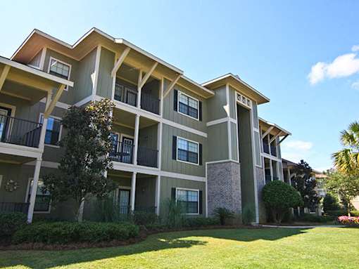 A large apartment complex with a green lawn in front.