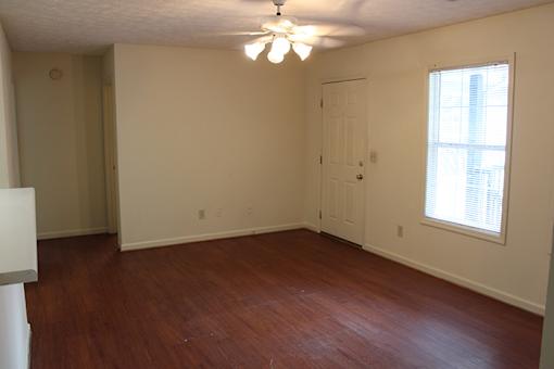 an empty living room with wooden floors and a white door