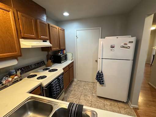 A kitchen with a white fridge and wooden cabinets.