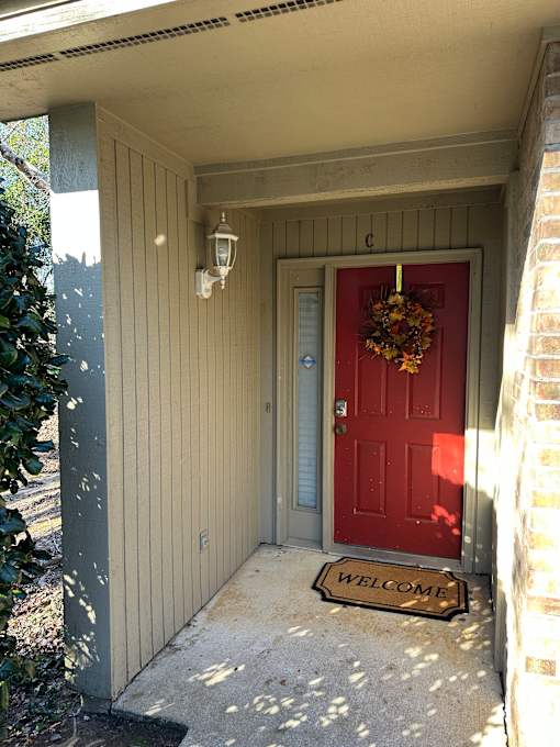 A red door with a wreath and a sign that says "welcome".