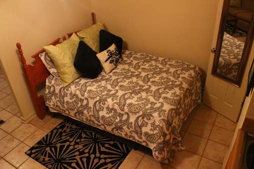 A bed with a paisley patterned comforter and a black and white pillow.