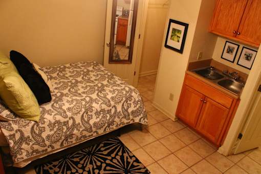 A bedroom with a patterned bedspread and a green pillow.