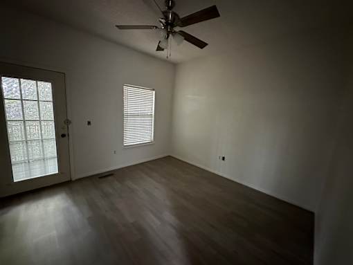 A room with a ceiling fan and a door leading to a balcony.