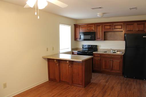a kitchen with wooden cabinets and a black refrigerator