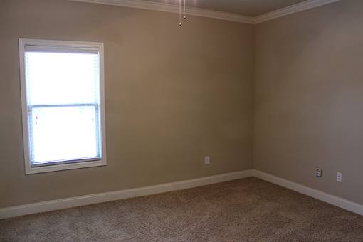 an empty living room with a window and carpet