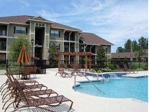 A pool area with chairs and a building in the background.