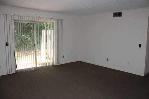 an empty living room with white walls and a sliding glass door