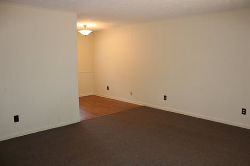 an empty living room with a hard wood floor and white walls