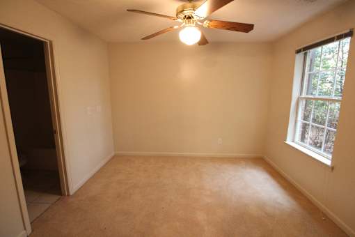 a empty living room with a ceiling fan and a window