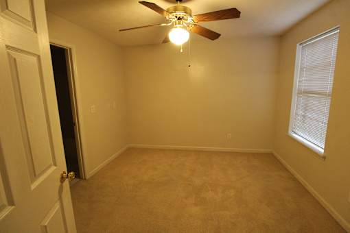 a empty room with a ceiling fan and a door