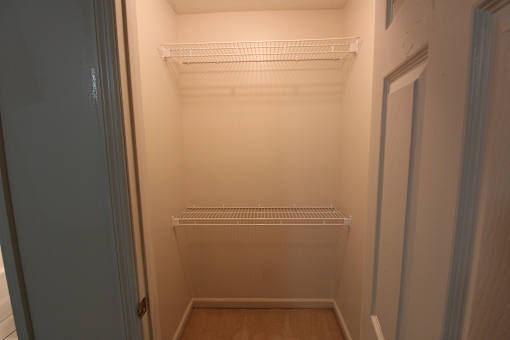 a walk in closet with empty shelves and a door