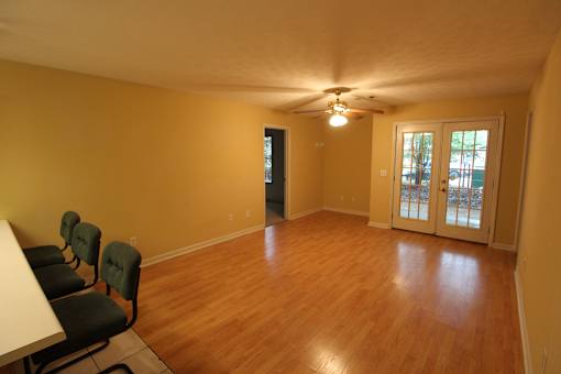 an empty living room with a wood floor and a door to a patio