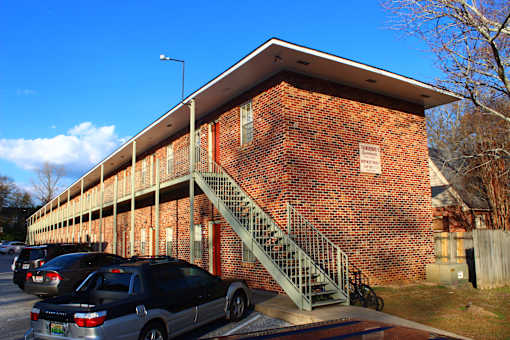 the side of a brick building with stairs and cars parked outside