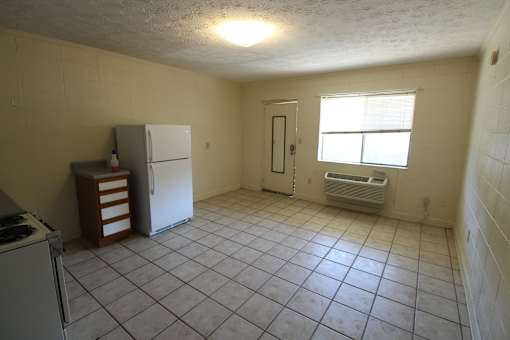 an empty kitchen with a refrigerator and a window