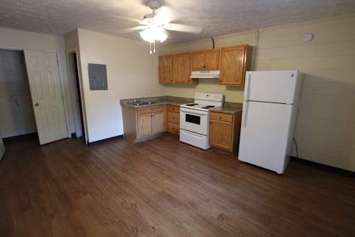 an empty kitchen with white appliances and wood floors