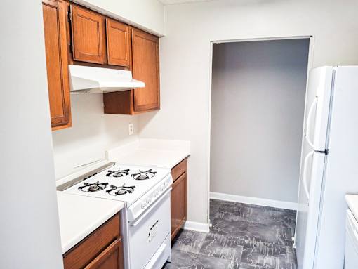 A kitchen with a white stove top and wooden cabinets.