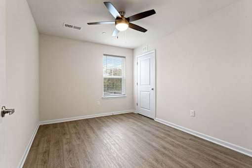 A room with a ceiling fan and a door.