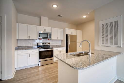 A kitchen with white cabinets and a granite countertop.