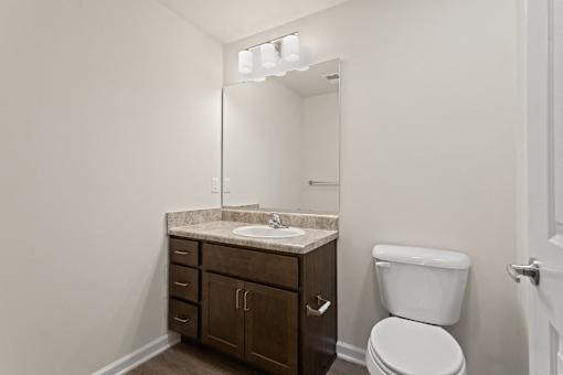 A bathroom with a toilet, sink, and cabinet.