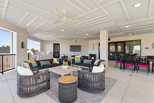 A modern outdoor living space with a white ceiling fan and a black and white striped rug.