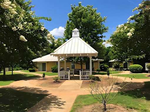 A gazebo is surrounded by trees and bushes.