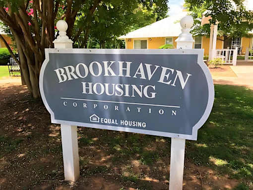 A sign for Brookhaven Housing Corporation stands in front of a building.