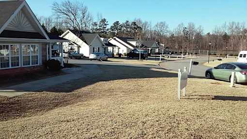 A grassy area with a sign and houses in the background.