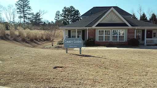 A sign in front of a house that says Country Gardens.