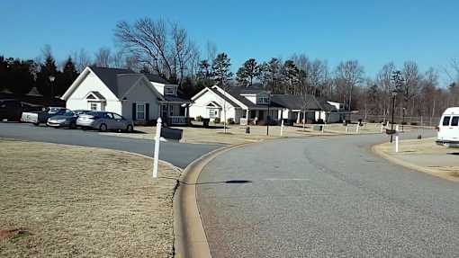 A residential area with houses and cars parked on the street.