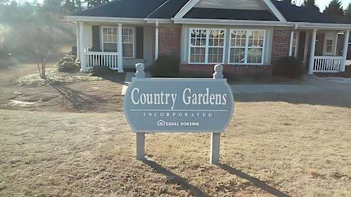 A sign in front of a house that says Country Gardens.