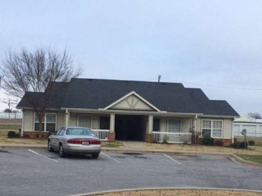 A silver car is parked in front of a house.