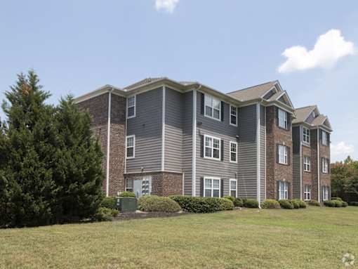 a large apartment building with a grass yard in front