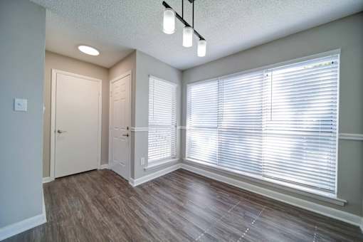 A room with a window covered by white blinds and a light on.