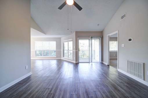 A room with a ceiling fan and sliding glass doors.