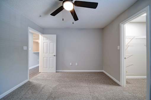 A room with a ceiling fan and carpeted floor.